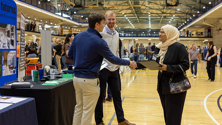 Ansaam Lateefuddin Khaja, right, a graduate student in economics, shakes hands with Branden Wagener, a company representative from Welltower.